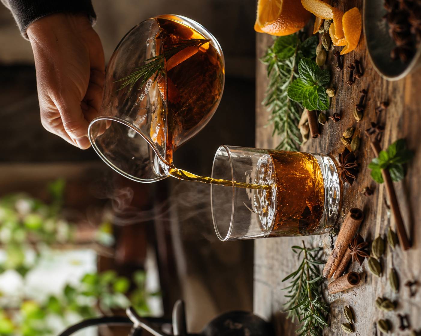Préparation d'une boisson épicée artisanale versée dans un verre avec épices sur table en bois