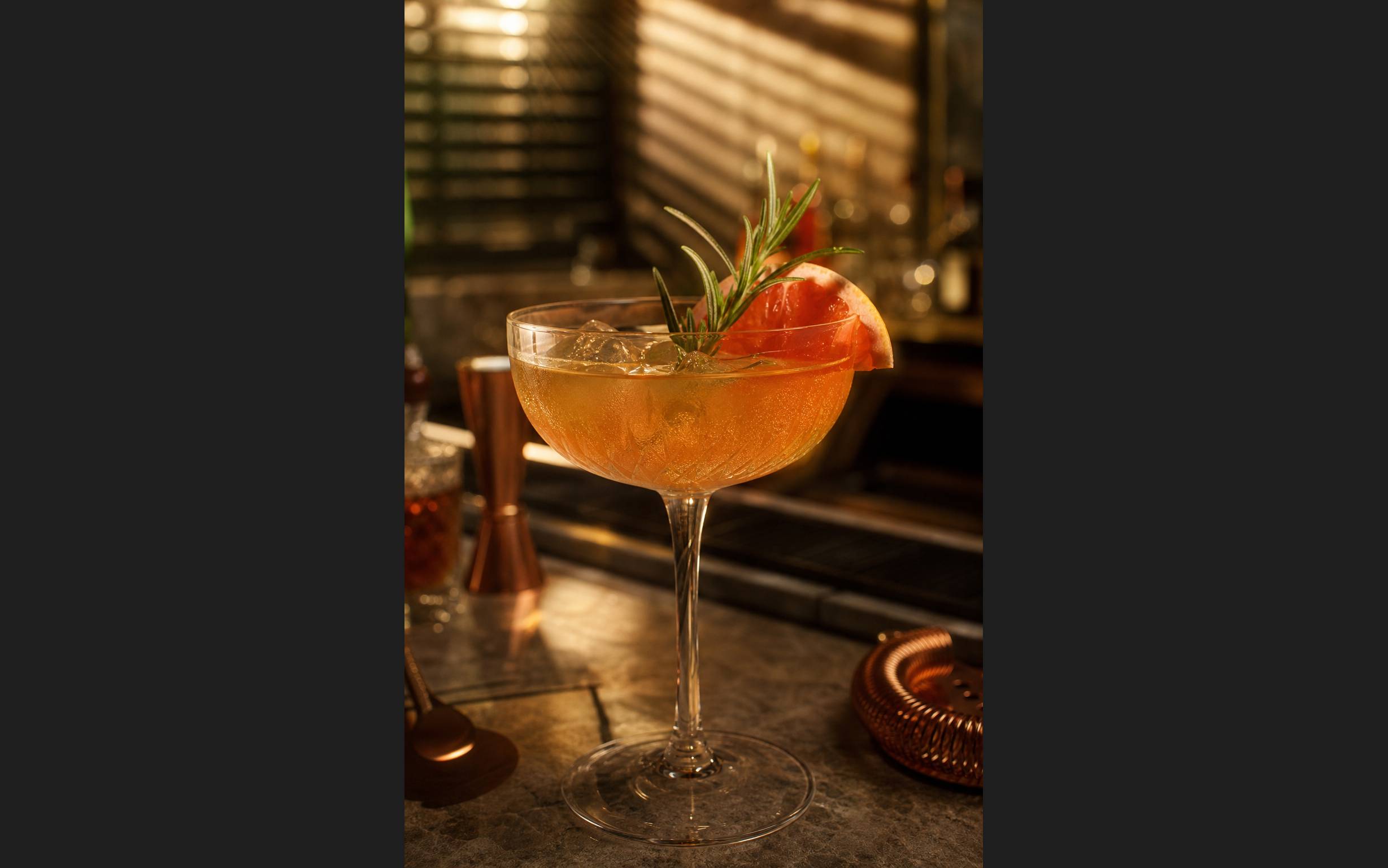 Cocktail artisanal garni de fruits frais dans un verre elegant au bar