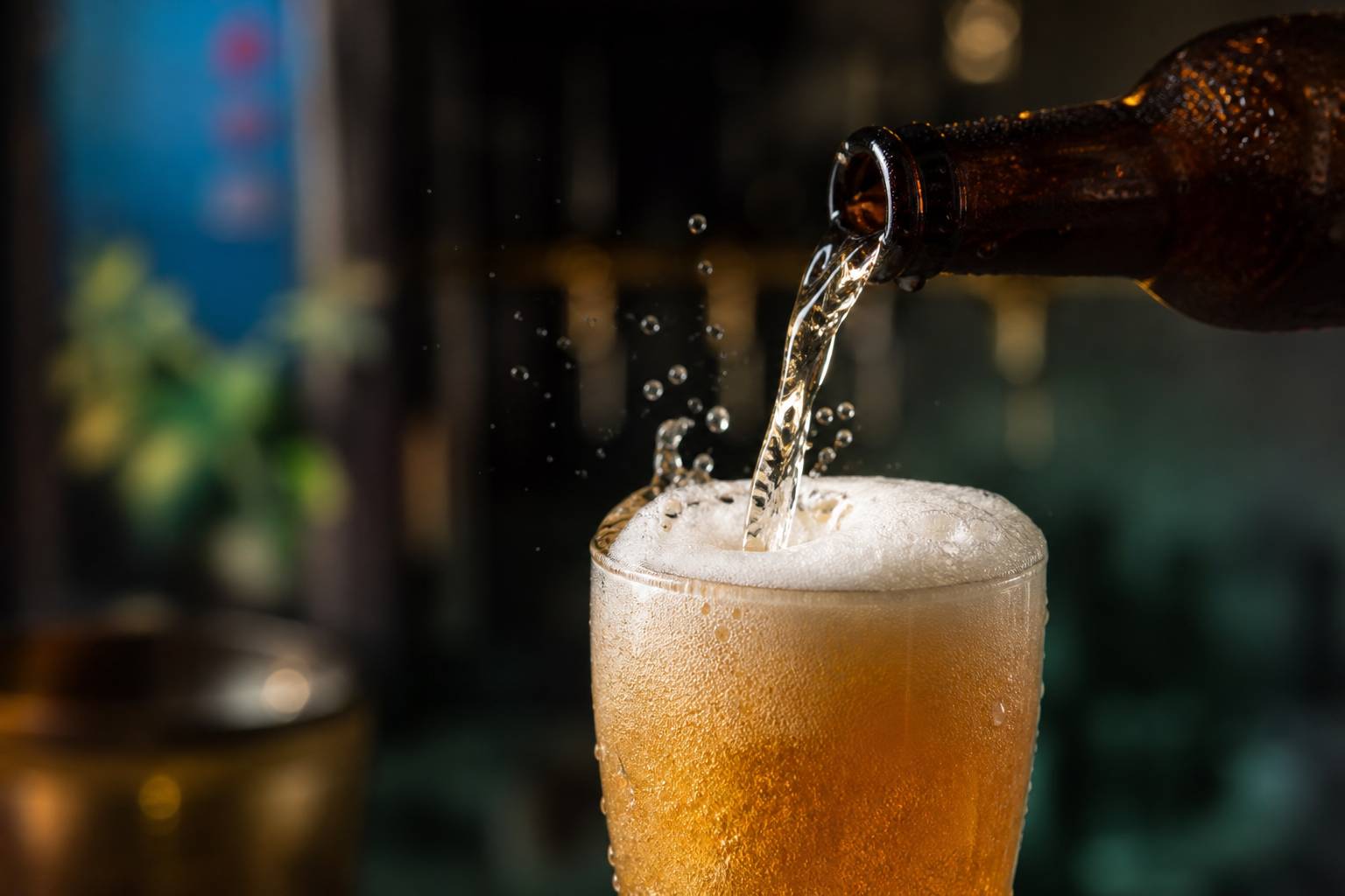 Versement de la Lagunitas 12th of Never Ale de la bouteille au verre avec éclaboussures et mousse