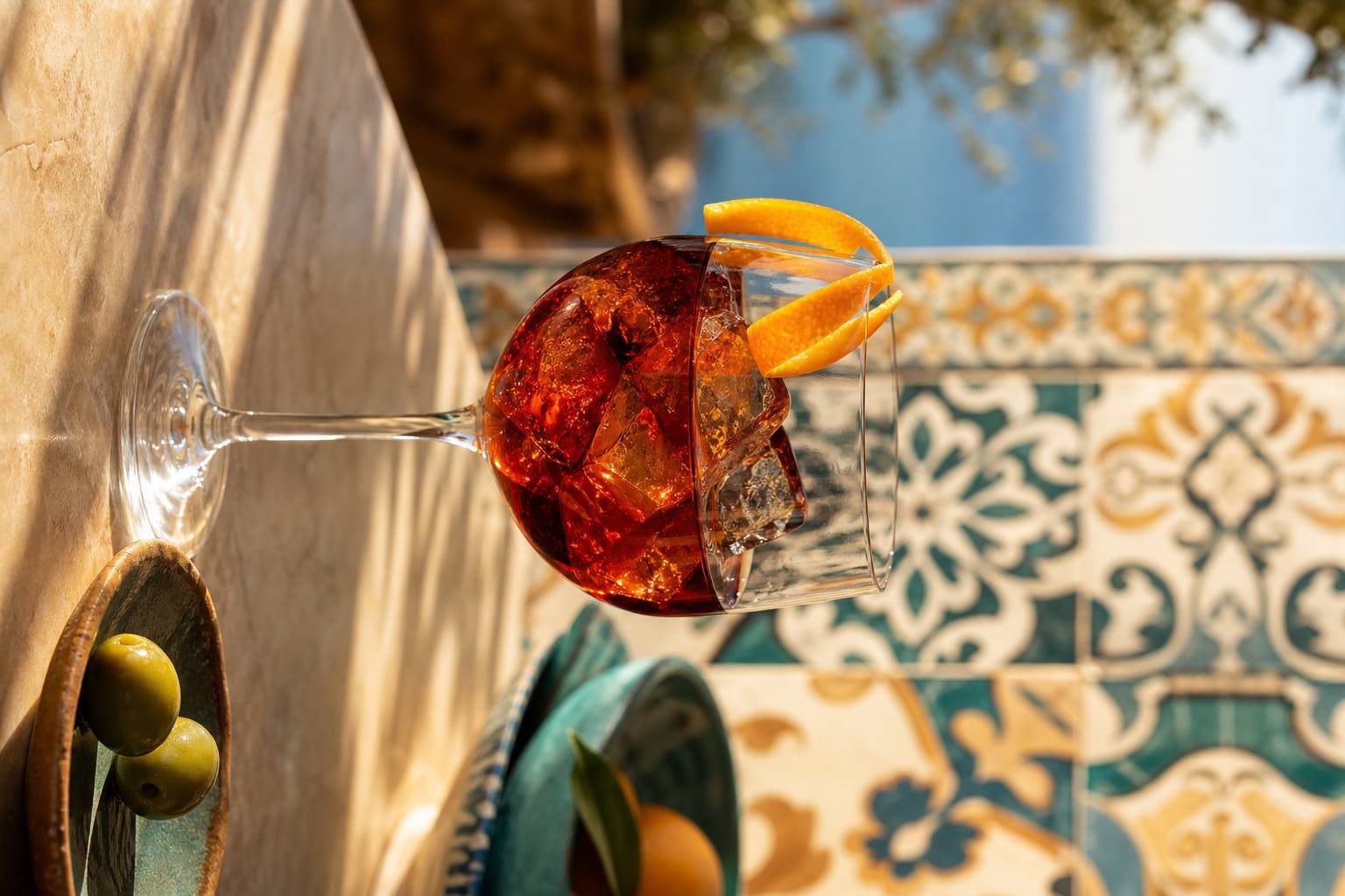 Verre de vermouth rouge espagnol sur glace avec zeste d'orange et olives sur fond de carrelage traditionnel